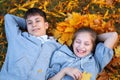 Girl and boy teenager having holiday in autumn city park, lying on grass, posing, smiling, playing and having fun. Bright yellow Royalty Free Stock Photo