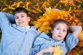 Girl and boy teenager having holiday in autumn city park, lying on grass, posing, smiling, playing and having fun. Bright yellow