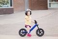 Girl boy toddler riding a balance bike bicycle in helmet on the road