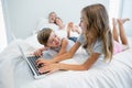 Girl and boy using laptop on bed in bedroom at home Royalty Free Stock Photo