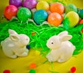 Two white porctlain rabbits near colorful bright eggs