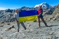 Ukrainian flag in the mountains hold by a tourist couple