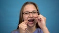 Girl with braces brushing your teeth with dental floss. A girl with colored braces on her teeth keeps her teeth clean. Royalty Free Stock Photo