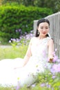 Girl bride in wedding dress with elegant hairstyle, with white wedding dress Sitting Leaning against the fence Royalty Free Stock Photo