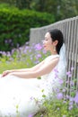 Girl bride in wedding dress with elegant hairstyle, with white wedding dress Sitting Leaning against the fence Royalty Free Stock Photo