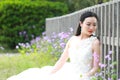 Girl bride in wedding dress with elegant hairstyle, with white wedding dress Sitting Leaning against the fence Royalty Free Stock Photo