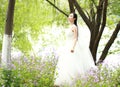 Girl bride in wedding dress with elegant hairstyle, with white wedding dress Standingin the grass by the river Royalty Free Stock Photo