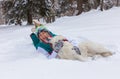 Girl lying down with shepherd dog on the snow, winter time Royalty Free Stock Photo