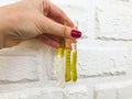 A girl with a bright red manicure holds gummy bright worms against the background of a white brick wall. sweets on a plastered Royalty Free Stock Photo