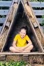 A girl in a bright yellow t-shirt sits in a small hut