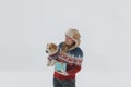 girl in a brown coat gives a Jack Russell Terrier a gift on a white background during a blizzard. The dog sits on the hands of a