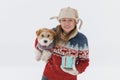 girl in a brown coat gives a Jack Russell Terrier a gift on a white background during a blizzard. The dog sits on the hands of a