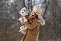 A girl in a brown hat with earflaps and a dog on the background of trees in the park. Portrait of a Jack Russell Terrier dressed