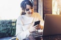 Girl browsing social networks on smartphone while sitting cafe. Blogger chatting with followers oncell phone coffee shop.Lifestyle Royalty Free Stock Photo