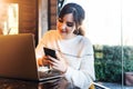 Girl browsing social networks on smartphone while sitting cafe. Blogger chatting with followers oncell phone coffee shop.Lifestyle Royalty Free Stock Photo