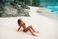 Girl Brunette with curly hair in a red bikini on the beach with white sand near the ocean on vacation. A beautiful model Royalty Free Stock Photo