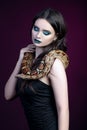 girl brunette green make up eyes close up portrait with a snake yellow brown mottled python on a black pink background