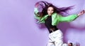 Girl brunette with long hair on a purple background jumps, flies. Dancing, hip hop Royalty Free Stock Photo