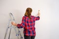 Girl brush paints the wall with white paint, copy space Royalty Free Stock Photo