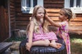 Girl brushing hair of her younger sister on the backyard of wooden house, healthy beauty Royalty Free Stock Photo
