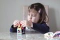 A girl is building a toy house sitting at a table Royalty Free Stock Photo