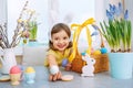 Girl in bunny ears on. Holyday morning at the table with Easter eggs basket. Kids celebrating Easter. Festive decoration Royalty Free Stock Photo