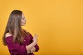 Girl in burgundy bluse over isolated orange background undecided pointing finger Royalty Free Stock Photo