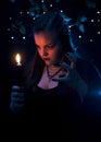 A girl with a burning candle stands in the dark, small lights are burning behind, illuminating the leaves. Autumn holiday Hallowe Royalty Free Stock Photo