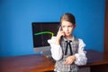 Girl in a business suit stands at the computer and talks on the phone Royalty Free Stock Photo