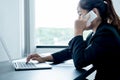 A girl businessman is talking on the phone with a smile while sitting at a desk and opening a modern working laptop in the office Royalty Free Stock Photo