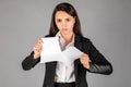 Girl or businesswoman tearing a piece of paper on a gray background