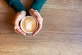 He is holding a cup of aromatic cappuccino