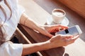 a girl in a cafe drinks coffee and uses the Internet in smart-phone. Workplace in a cafe.