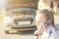 Girl calling. Broken car on a background. Woman sit on a wheel. young woman repair a car. Natural background. Car accide Royalty Free Stock Photo