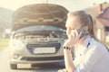 Girl calling. Broken car on a background. Woman sit on a wheel. young woman repair a car. Natural background. Car accide Royalty Free Stock Photo