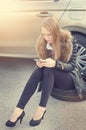 Girl calling. Broken car on a background. Woman sit on a wheel. young woman repair a car. Natural background. Car accide