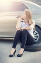 Girl calling. Broken car on a background. Woman sit on a wheel. young woman repair a car. Natural background. Car accide Royalty Free Stock Photo