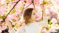 Girl on calm face standing between sakura branches with flowers, defocused. Cute child enjoy nature on spring day