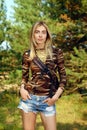 Girl in camo shirt, jeans shorts with backpack on hiking trail in forest Royalty Free Stock Photo