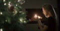 A girl with a candle in her hands sits by the Christmas tree. In the background, a fire burns in a fireplace. Christmas Royalty Free Stock Photo