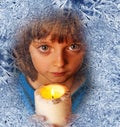 Girl with candles looking through a frosted window Royalty Free Stock Photo