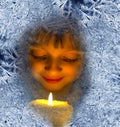 Girl with candles looking through a frosted window Royalty Free Stock Photo