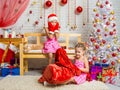 Girl in a cap and mittens of Santa Claus saw that bag climbs another girl Royalty Free Stock Photo