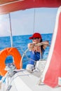 Girl captain on board of sailing yacht on summer cruise. Travel adventure, yachting with child on family vacation. Royalty Free Stock Photo