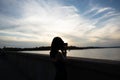 Girl capturing the beautiful view of a tranquil seascape with a camera against the sky at sunrise Royalty Free Stock Photo