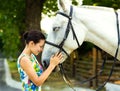 The girl caresses with a horse. The horse covers its eyes with pleasure