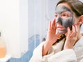 The girl is caring for the face. Cosmetic black mask. A woman brings beauty to her face, gets rid of black dots with a black mask