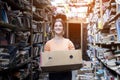 Girl carries a box of books in the library, a portrait of a bookseller against a background of a bookstore