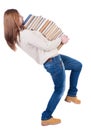 A girl carries a heavy pile of books. back view. Rear view peopl Royalty Free Stock Photo