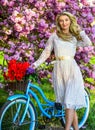 Girl carry flowers in retro bicycle. spring beautiful woman in dress. girl vintage bike. blooming sakura tree. summer Royalty Free Stock Photo